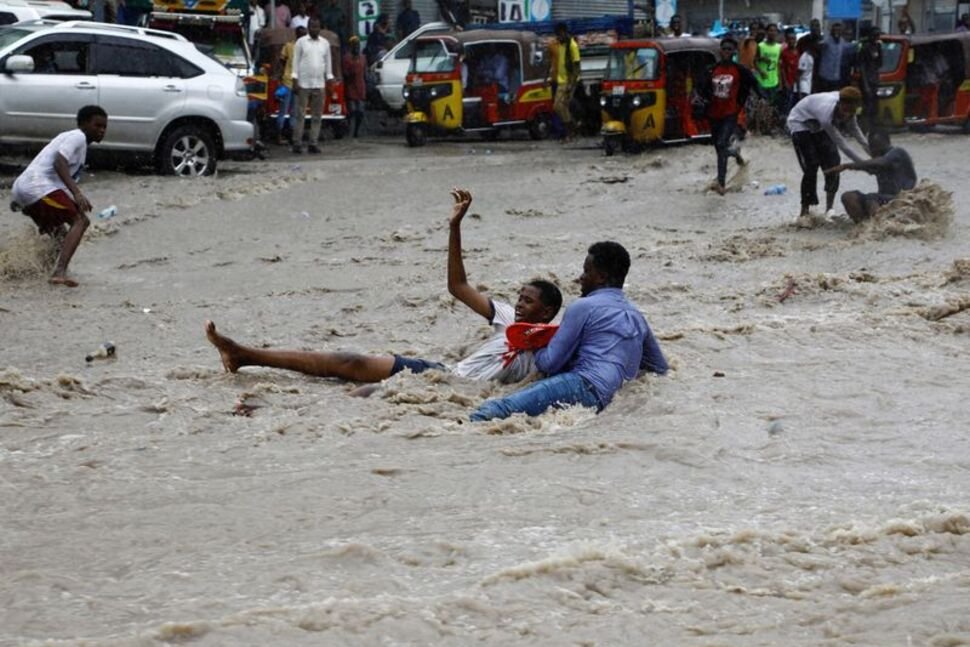 FILE PHOTO: A man attempts to rescue a boy from raging flood waters following heavy rains in Mogadishu, Somalia November 9, 2023. REUTERS/Feisal Omar/File Photo